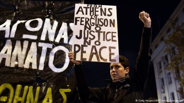 Göstericinin elindeki pankartta, "Ferguson'dan Atina'ya Ne adalet var Ne de barış" yazıyor