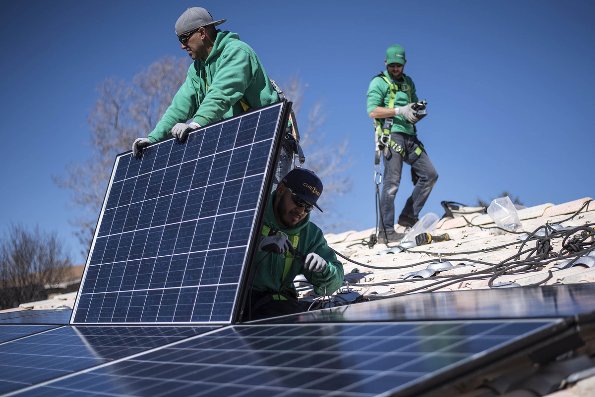 Çalışanlar Albuquerque, New Mexico eyaletinde solar panellerini binanın çatısına yerleştiriyor.