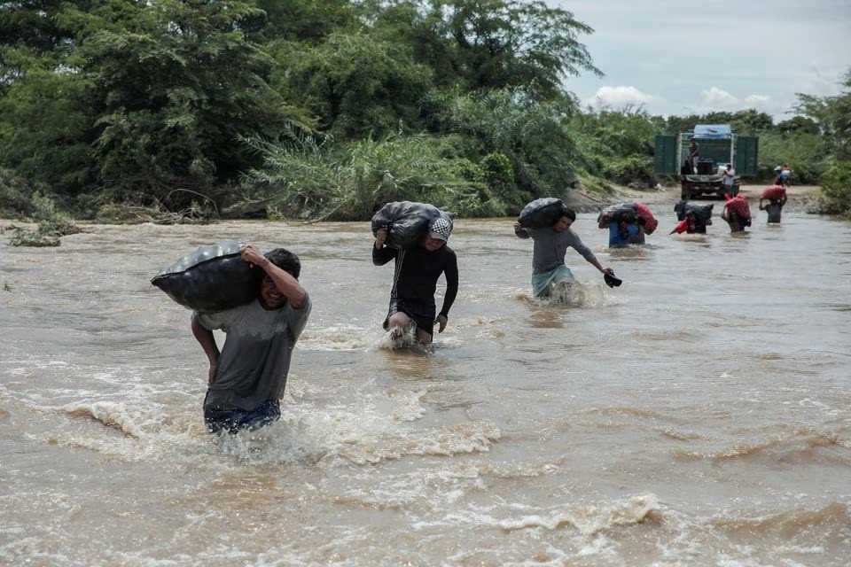 Fotoğraf: Sebastian Castaneda / Reuters - 11 Mart 2023, Piura, Peru'da yaşayanlar, Yaku Kasırgası'nın doğrudan etkisiyle oluşan yağmurlar nedeniyle taşan dereden sebze çuvalları taşıyor.