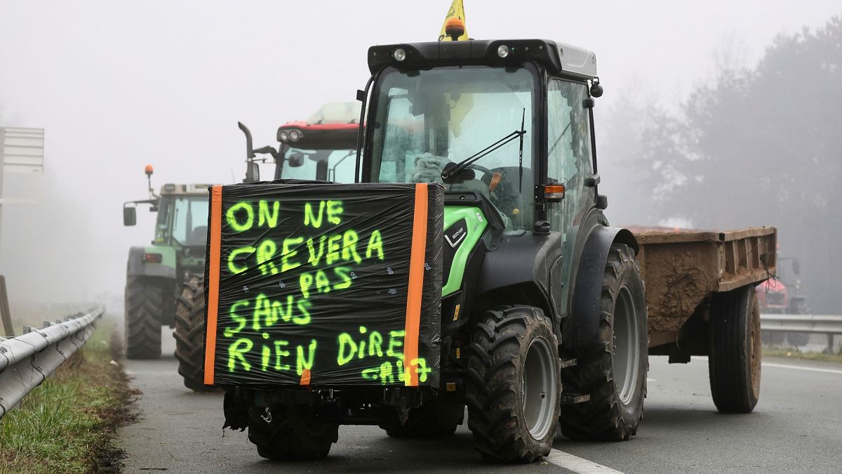 Fransa'nın güneybatısındaki Agen yakınlarındaki bir otoyolda "Tek kelime etmeden ölmeyeceğiz" yazan bir poster taşıyan bir traktör park edilmiş durumda.